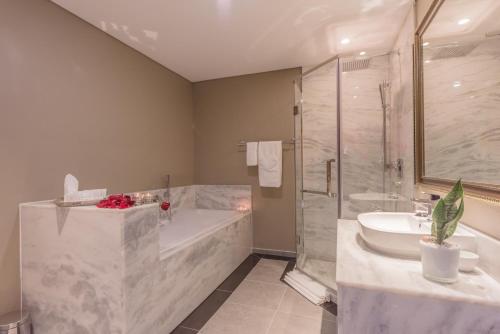 a bathroom with a tub and a shower and a sink at Flamingo Villas Boutique Hotel in Walvis Bay