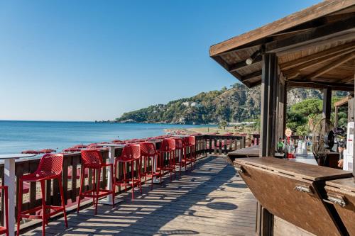 a row of red chairs sitting on a pier next to the beach at Club Esse Sunbeach in Squillace