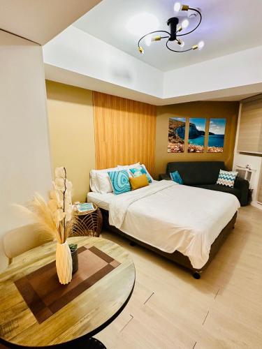 a bedroom with a bed and a table and a couch at Kaiah's Haven at Azure North San Fernando Pampanga in San Fernando