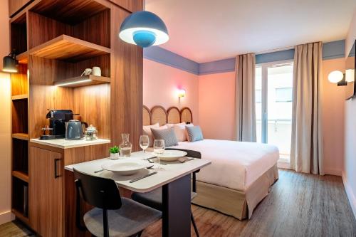 a hotel room with a bed and a table with wine glasses at Appartements RockyPop Marseille in Marseille