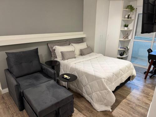 a bedroom with a bed and a chair at Studio no Coração do Jardins Moderno e Sofisticado in São Paulo