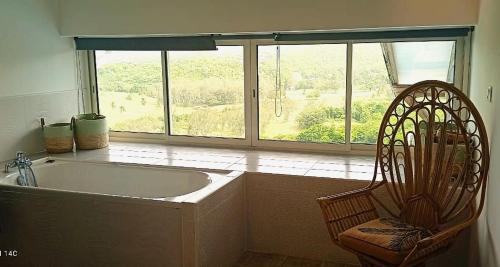 a bath tub in a room with a large window at La Maison Bwa in Les Trois-Îlets