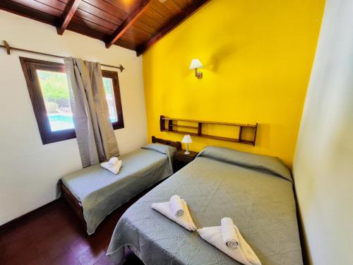 two beds in a room with yellow walls at Hotel Spileon in Villa Gesell