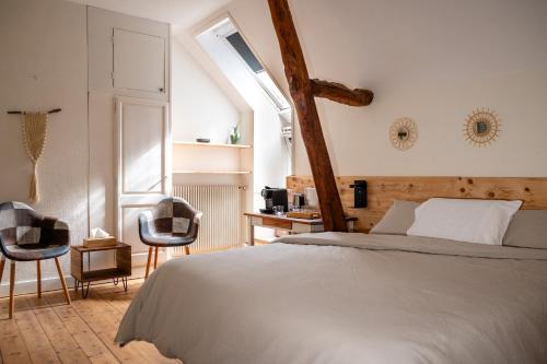a bedroom with a large bed and two chairs at B&B BienViennue in Marcilly-sur-Vienne