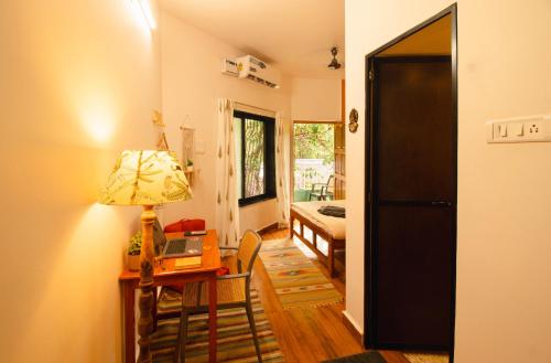 a room with a desk and a table with a lamp at Odd Table-Social Homestay in Mandrem