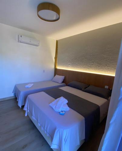 two beds in a hotel room with blue sheets at Bangalo Aconchegante - Praia Dulé ES - Suite 1 in Guarapari