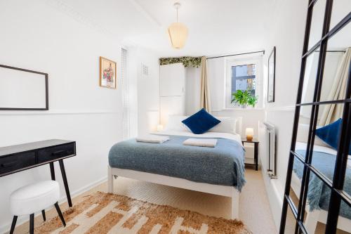 a white bedroom with a bed and a desk at Stylish 2 bed Central London in London
