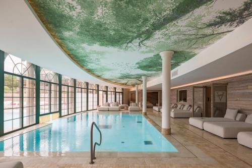 a hotel pool with a painting on the ceiling at Les Violettes Hotel & Spa in Jungholtz