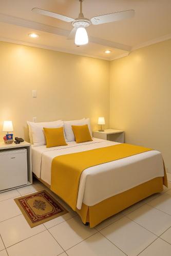 a bedroom with a large bed with yellow and white pillows at Hotel Ibiá in Montenegro
