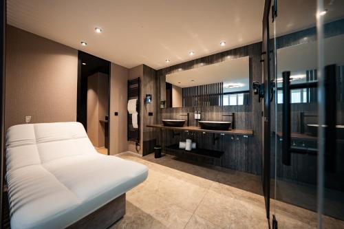 a bathroom with two sinks and a white bed at Anatura Hotel Luxembourg in Weiswampach