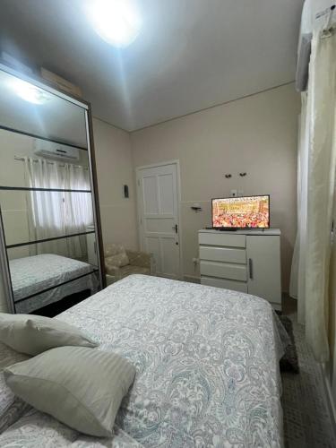 a bedroom with a bed and a mirror and a dresser at Casa Centro de Caraguatatuba in Caraguatatuba