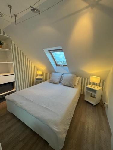 a bedroom with a white bed with a skylight at Maison port guillaume in Dives-sur-Mer