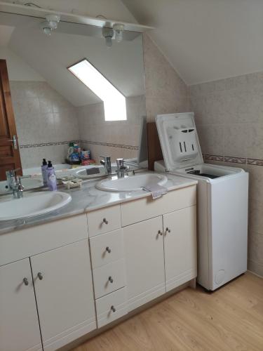 a bathroom with two sinks and a refrigerator at Gîte de la Forêt in Saint-Jeanvrin