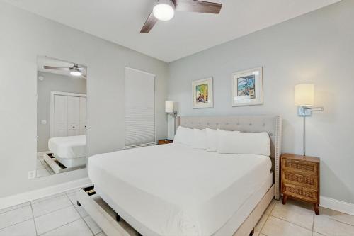 a white bedroom with a large bed and a mirror at Topsail Village #511 - Beach Moon in Santa Rosa Beach