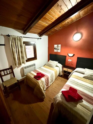 two beds in a room with red walls at Casa Enry in Alcalá de la Selva