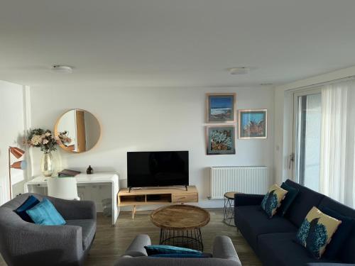 a living room with two blue couches and a tv at Seaview West Coast - Exceptional - 2 Bedrooms Sleeps 5 -Stunning Sea Views - 500 metres to Beach in Bournemouth