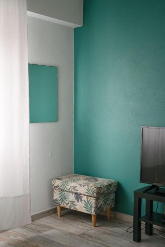 a room with a television and a ottoman next to a wall at A Praia My Own Paradise T2 1º Andar in Figueira da Foz
