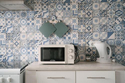 a kitchen with blue and white tiled walls and a microwave at A Praia My Own Paradise T2 1º Andar in Figueira da Foz