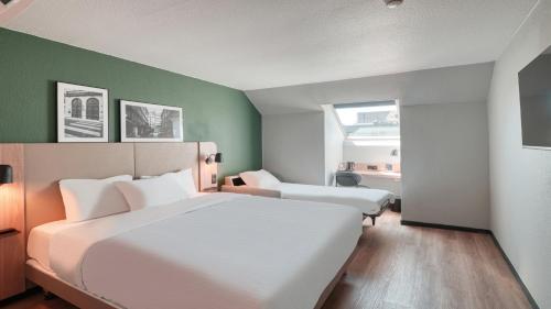 a bedroom with two beds and a green wall at Campanile NATURE - Compiegne in Compiègne