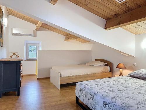 two beds in a room with wooden ceilings at Coeur de pierre in Vallon-Pont-dʼArc
