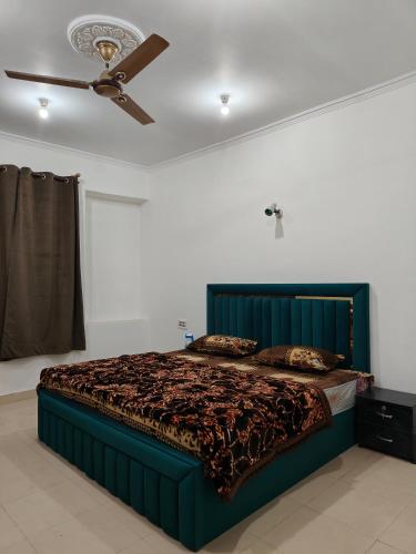 a bedroom with a green bed with a ceiling fan at Hotel Sada Bahar in Srinagar