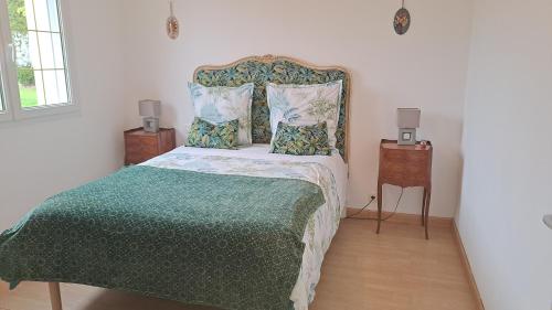 a bedroom with a bed with a green blanket and pillows at gîte de bon air in Sens-de-Bretagne