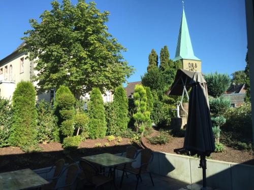 a patio with an umbrella and a church at Hotel Grüner Baum in Hamm