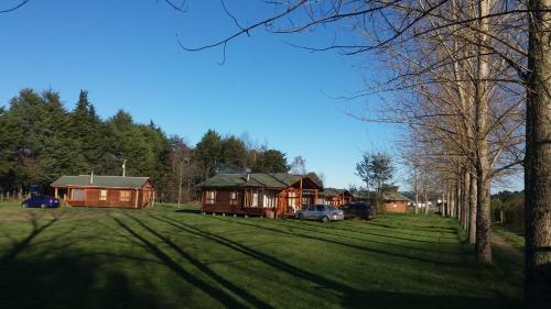 a group of cottages with cars parked in a field at Cabañas De Madera in La Unión