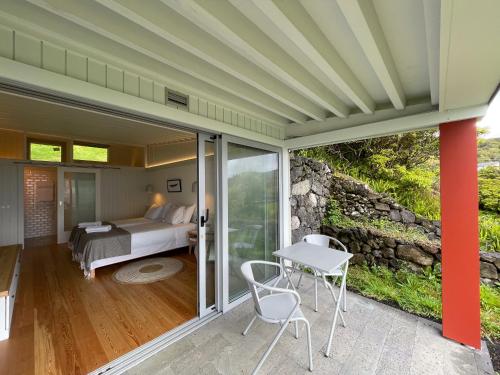a bedroom with a bed and a table and chairs at Abrigos Baleeiros Turismo Rural in Feiteira