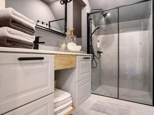 a bathroom with a glass shower and a sink at Ferienwohnung LA MAISON mit Sauna am See in Neuenkirchen