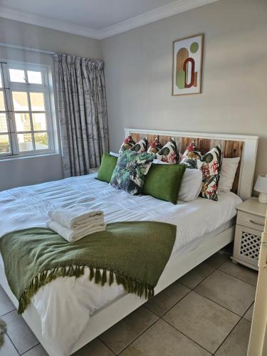 a bedroom with a large white bed with green pillows at Arabella By The Sea in Port Alfred