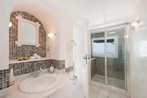 a white bathroom with a sink and a shower at Anastasis Apartments and Spa in Imerovigli
