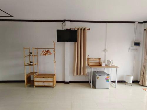 a room with white walls and a table and a television at Langkao Homestay Kohlibong หลังเขาโฮมสเตย์ เกาะลิบง in Ko Kwang