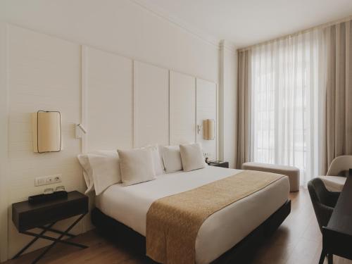 a bedroom with a large bed and a chair at Catalonia Molina Lario in Málaga
