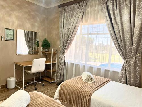 a bedroom with a bed and a desk and a window at The Bloemhof Stay in Bloemhof