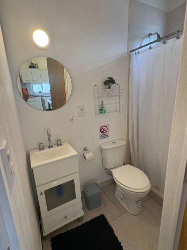 a bathroom with a toilet and a sink and a mirror at Dpto Centrico 2 Hab con Split Frío Calor cada Habitación in Mercedes