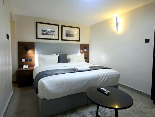 a hotel room with a large bed and a table at Five Clover Hotel, Ilupeju in Lagos