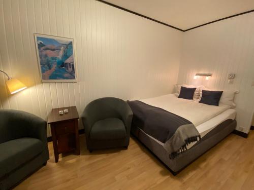 a bedroom with a bed and a chair and a table at Offersøy Feriesenter in Offersøy