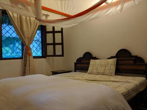 a bedroom with two beds and two windows at Nelion Villas in Mambrui