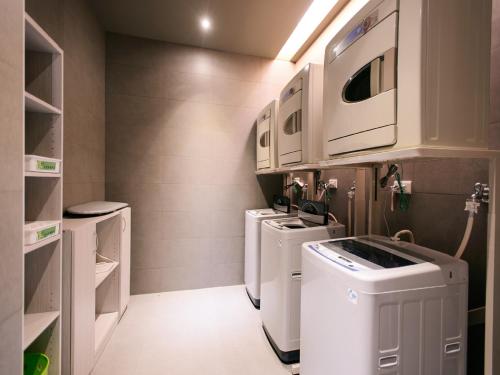 a laundry room with three washer and dryer at Kiwi Express Hotel - Jiuru Rd in Kaohsiung