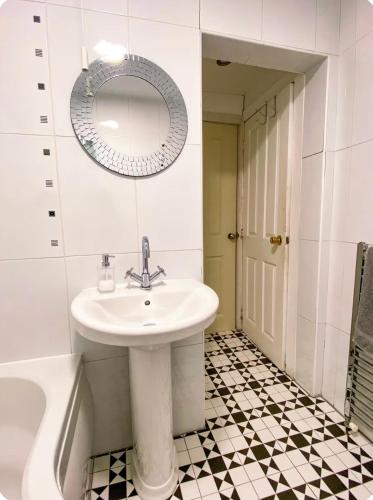a bathroom with a sink and a mirror and a tub at Light & Spacious Loch Lomond Apartment in Alexandria
