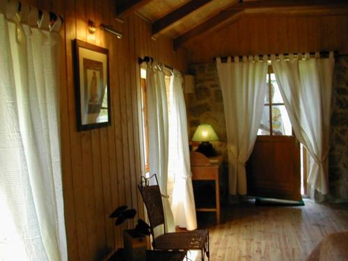 Habitación con cortinas blancas, mesa y lámpara. en L'AUBERGE CHEZ LEON, en Le Chambon-sur-Lignon