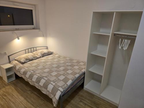 a bedroom with a bed and a tv and shelves at Rent0nline Brwinow Rooms in Brwinów