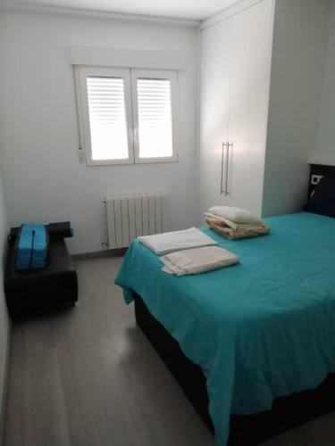 a bedroom with a bed and a chair and two windows at Como en tu casa in Zaragoza