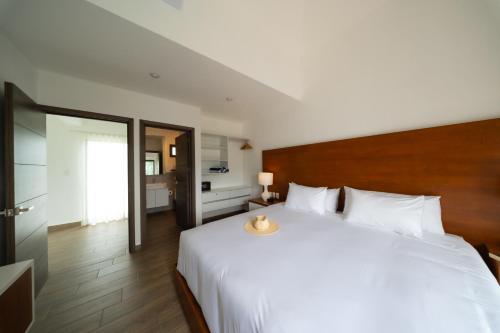 a bedroom with a large white bed with a wooden headboard at Designer Villa with Direct Pool Access in Monterrico