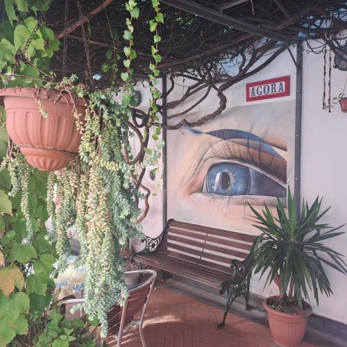 a wall with a bench and a painting of a eye at Agorà Hostel in Pompei