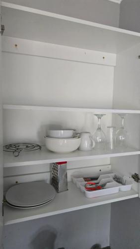 a white shelf with bowls and dishes on it at HUZULA Royal Residence in Empangeni