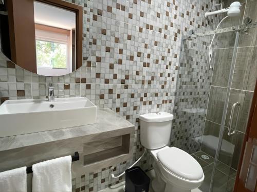 a bathroom with a toilet and a sink and a mirror at Sun Route Hotel in Cabo de Santo Agostinho