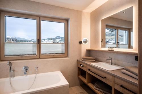 a bathroom with a tub and a sink and two windows at Seefeldstub'n in Kirchberg in Tirol