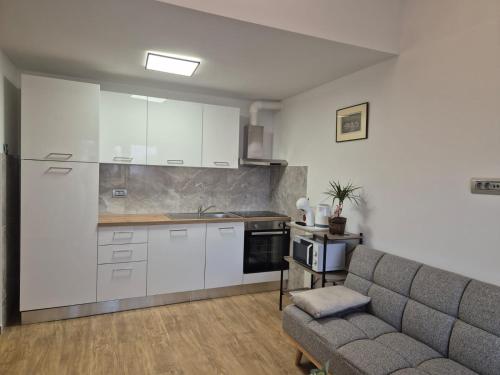 a kitchen with white cabinets and a couch in a room at Apartman Meghan in Pula